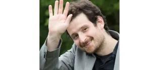 A photgraph of Dr Pasquale Minervini in wihch he is waving with his right hand.