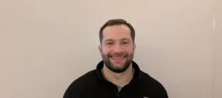 A photograph of Euan Morse, a tall man with black hair and a bear.