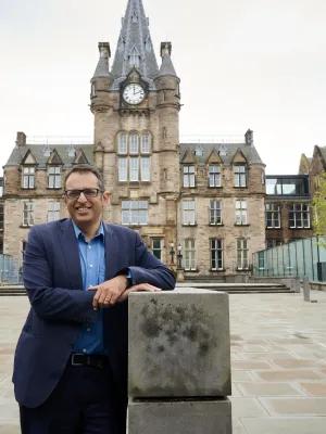 A photograph of Professor Kev Dhaliwal outside the front of the Edinburgh Futrures Institute